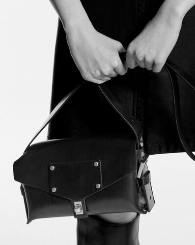 Photo en noir et blanc dune femme portant un sac à main en cuir noir.